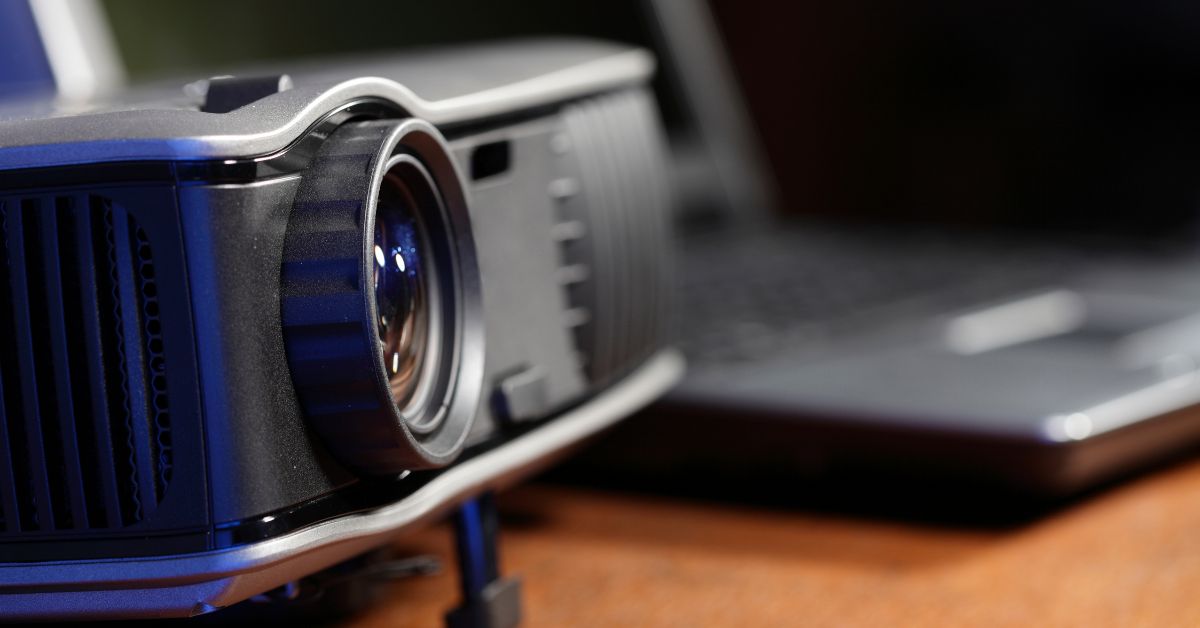 Projektor med laptop i baggrunden